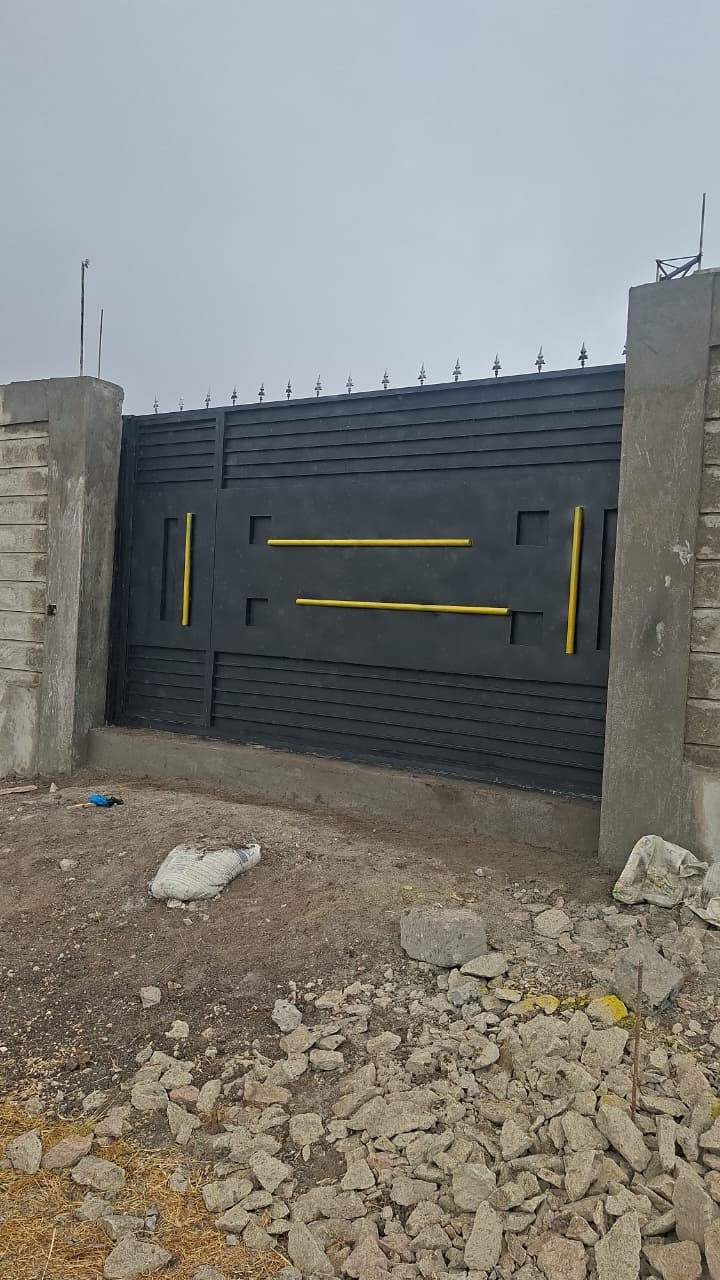 Black steel driveway gate with gold decorative details